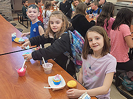  Children Sitting at a table eating lunch.