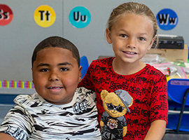  Two students posing for a photo in  the classroom. 